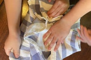 Kids hand wrapping ice cream in a dishtowel.
