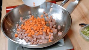 Diced carrots and spam in a skillet.