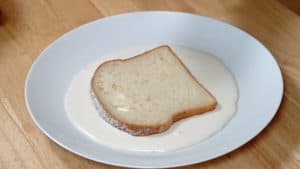 A slice of white bread sitting in a pool of melted vanilla ice cream.