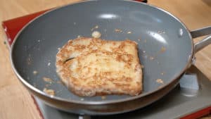A golden brown slice of french toast in a non-stick frying pan.