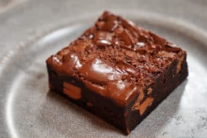 A square of brownie on a gray plate.