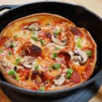 A combination pizza in a cast iron skillet.