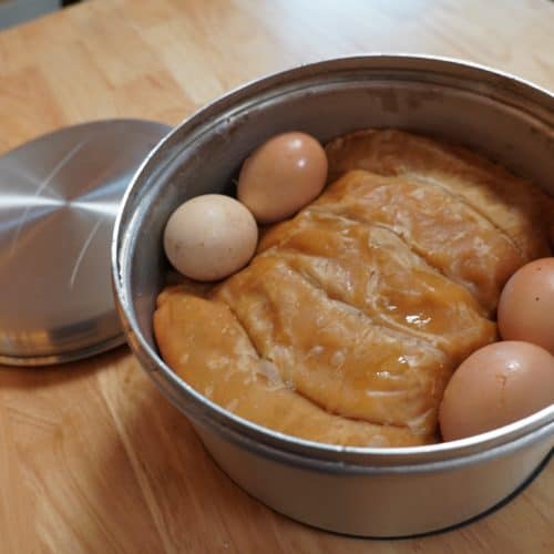 A metal tin with jachnun and eggs.
