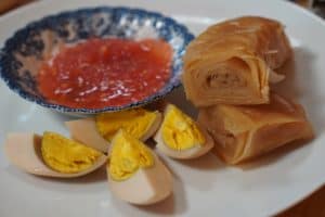 A layered pastry with quartered hard boiled egg and a saucer of tomato sauce.