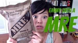 Emmy holding up an MRE with a surprised expression. Green text saying 