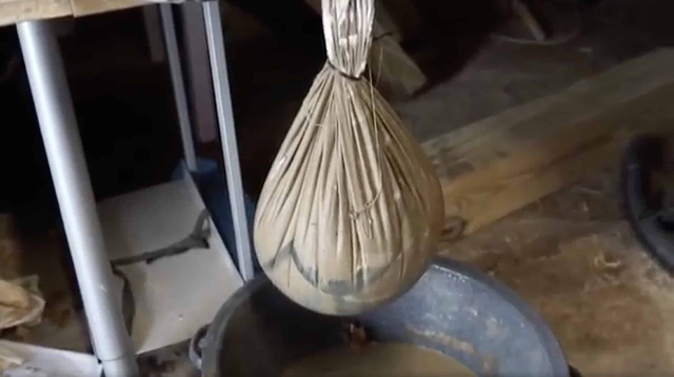 Removing excess water from clay in a cloth bag. 