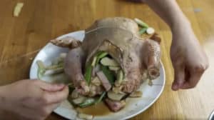 A raw chicken stuffed with green onions and bamboo shoots.