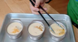 A pair of chopsticks stirring an egg into batter.