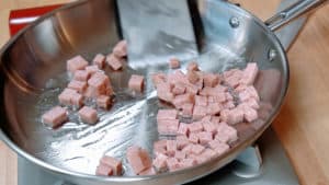 Cubes of spam frying in a skillet.