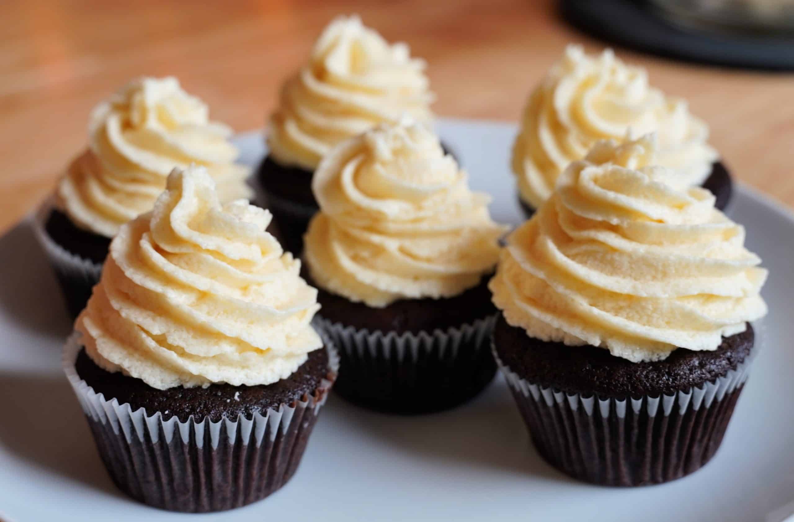 Six chocolate cupcakes topped with swirls of cream. 