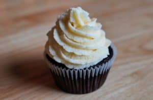 A chocolate cupcake topped with a swirl of white vegan buttercream.
