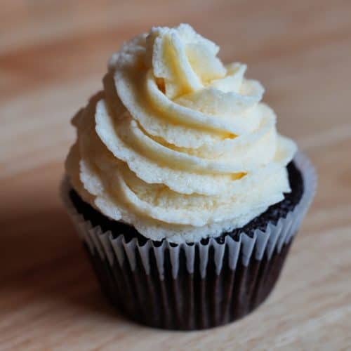 A chocolate cupcake topped with a swirl of white vegan buttercream.