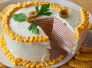 There is a "cake" sliced with one piece on a serving utensil. The cake consists of layers of bologna and frosting.