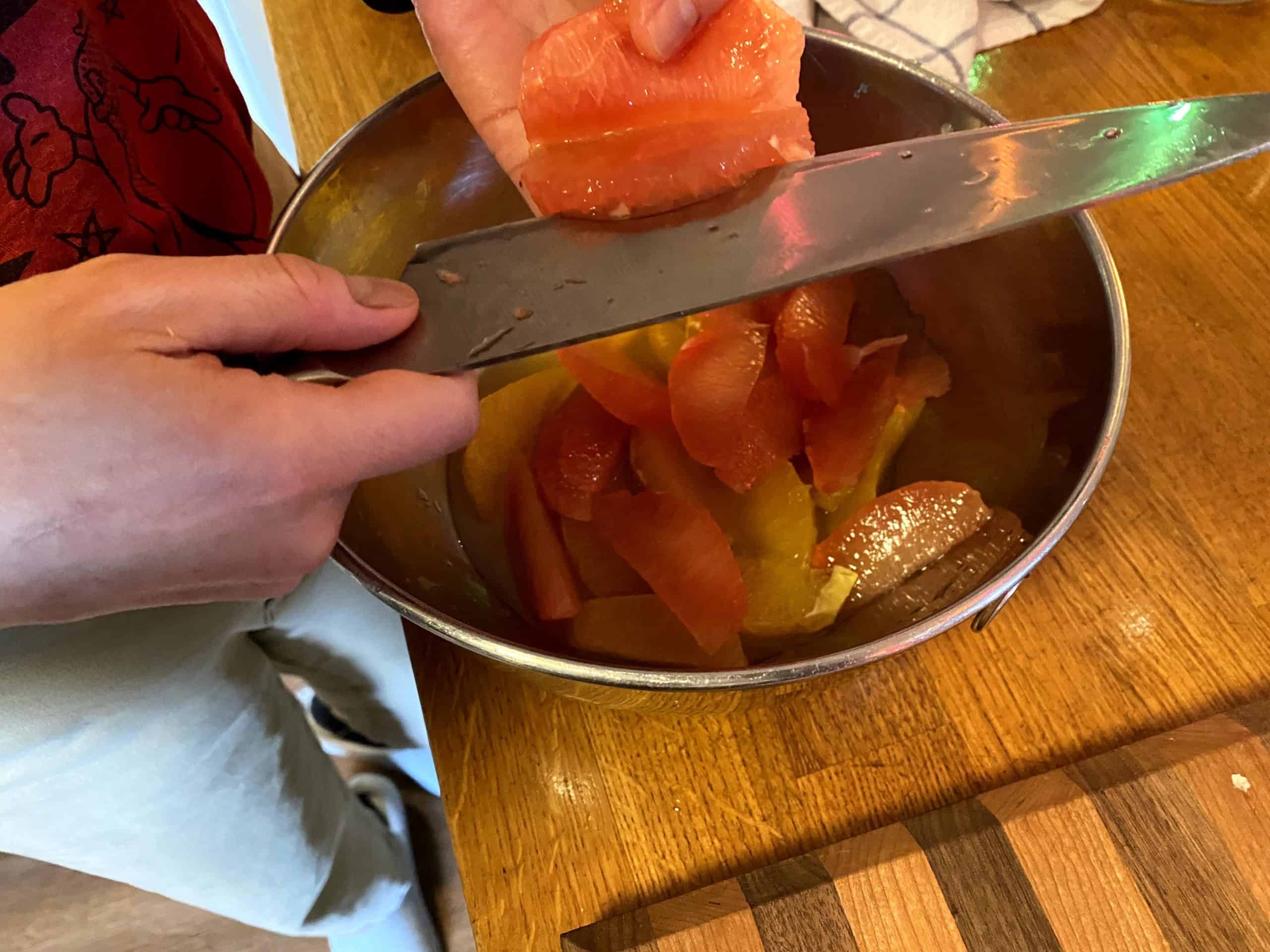 Supremeing pink grapefruit with a knife.