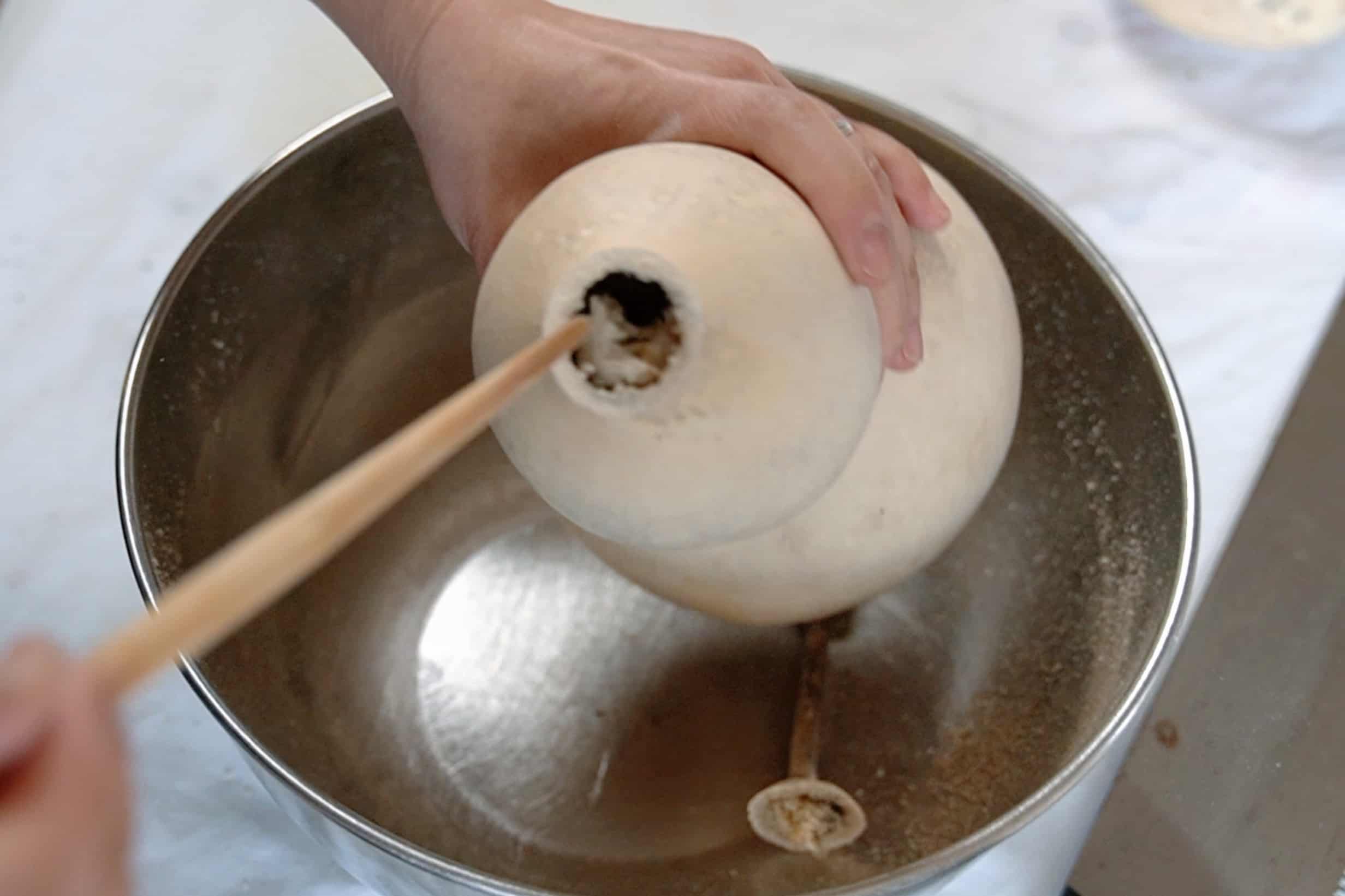 Using a stick to clean out a dried bottle gourd.