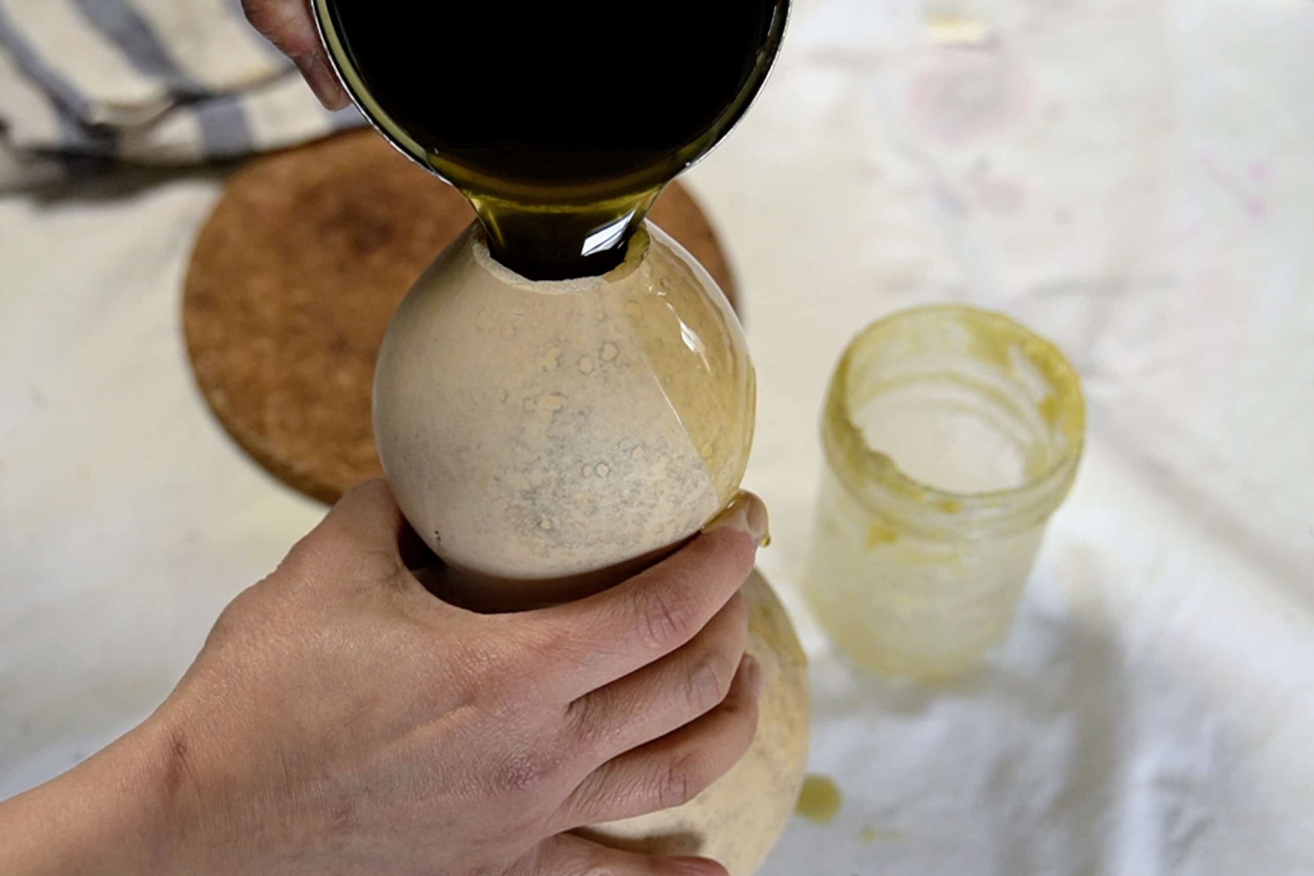 Pouring melted beeswax into a dried bottle gourd. 