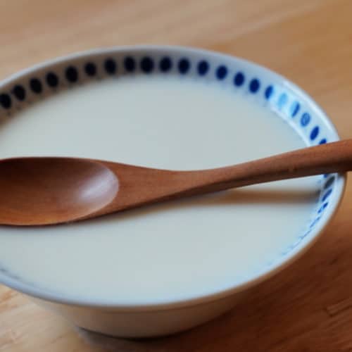 A bowl of ginger milk curd with a wooden spoon.