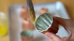 Coating a canele mold with butter with a pastry brush.