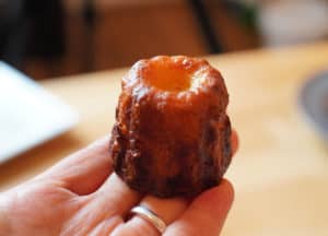 A single canelé perched on a hand.