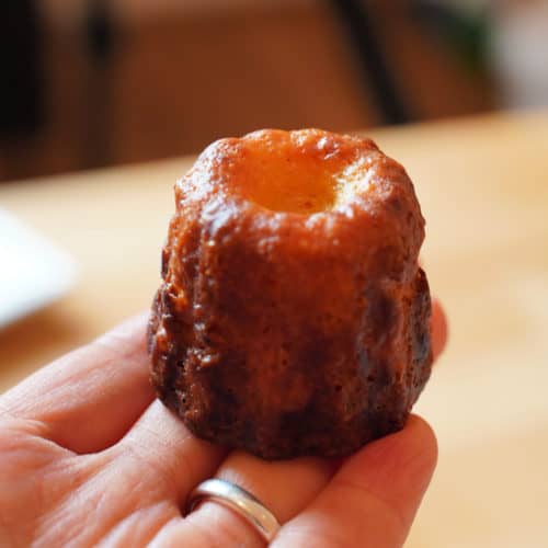 A single canelé perched on a hand.