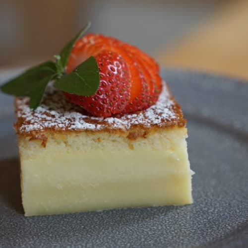 Triple layered cake with powdered sugar and strawberries on top