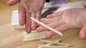 Open hands holding up raw French fry.