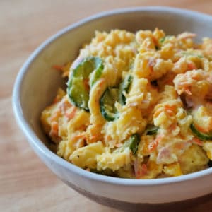 A bowl of japanese style potato salad with cucumbers and carrots.