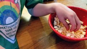 Boy's hand reaching into bowl of popcorn.