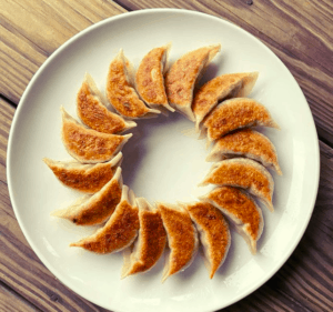 Japanese dumplings arranged on a plate in a circling, spiral pattern.