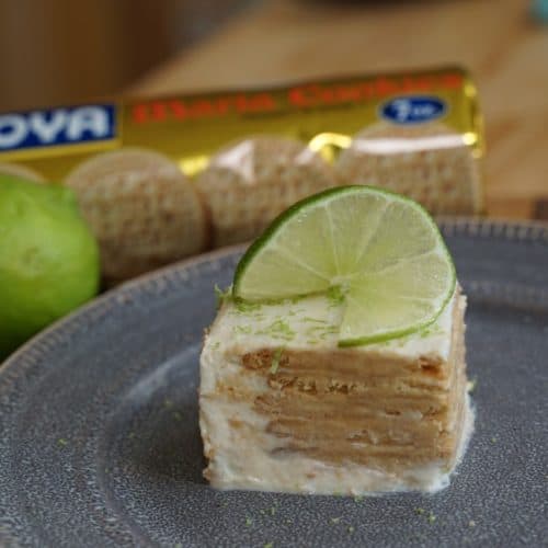 Lime Maria Icebox cake on a plate with a lime and a package of Goya biscuits in the background.