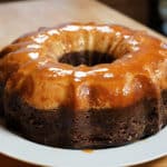 Chocolate cake on white plate with caramel flan layer on top.