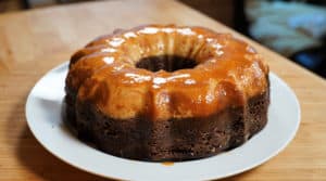 Chocolate cake on white plate with caramel flan layer on top.