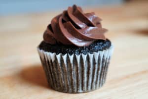 A chocolate cupcake made with greens topped with chocolate frosting.