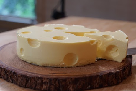 Whole cheese cheesecake with slice being removed.