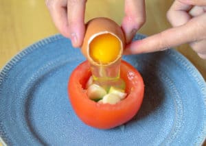 Pouring an egg into a tomato.