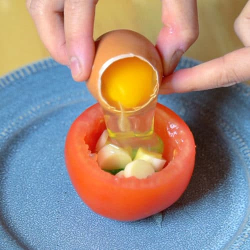 Pouring an egg into a tomato.