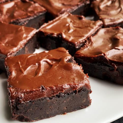 A plate of fudgy zucchini brownies with a chocolate frosting.