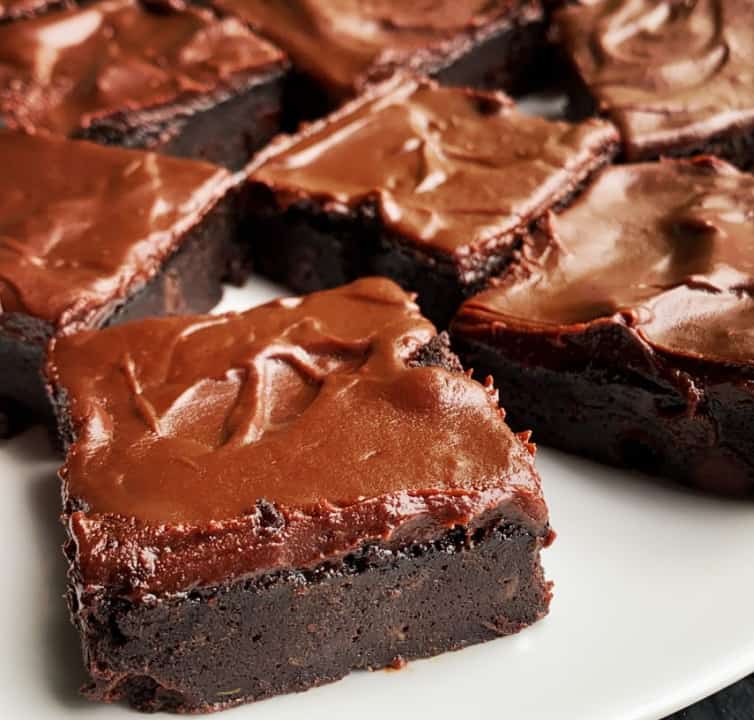 A plate of fudgy zucchini brownies with a chocolate frosting.