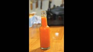 Orange hot sauce in a clear antique bottle.