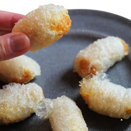 Fingers holding a rice paper chicken nugget.