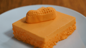 Bright orange square of Jell-O salad topped with a bright ornage circus peanut.