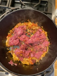 Bison meat in cast iron pot with onions, garlic, etc.