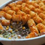 A hotdish casserole topped with tater tots with a scoop taken out of it.