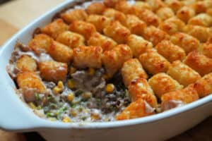 A hotdish casserole topped with tater tots with a scoop taken out of it.