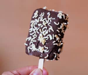 A chocolate dipped ice cream bar coated in with instant ramen.