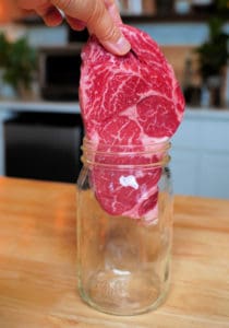 A raw steak placed into a canning jar.