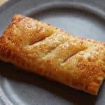 A golden brown homemade McDonald's apple pie on a grey plate.