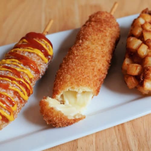 Three Korean style hot dogs on a plate.