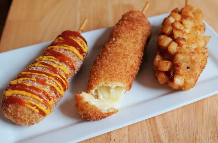 Three Korean style hot dogs on a plate.