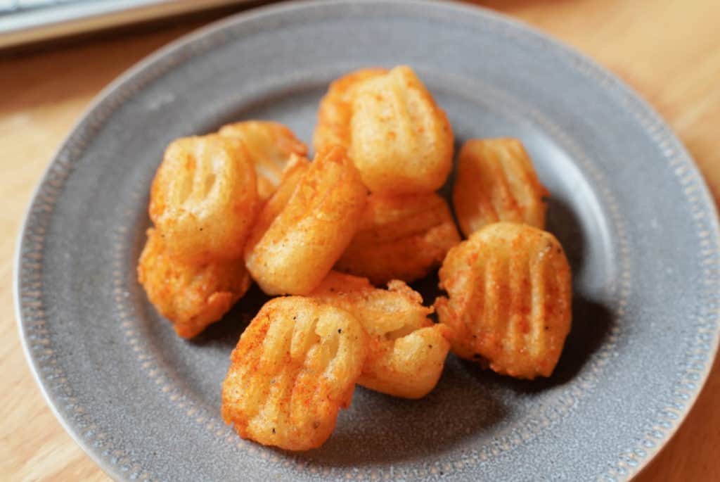 A grey plate with golden brown potato pillows.